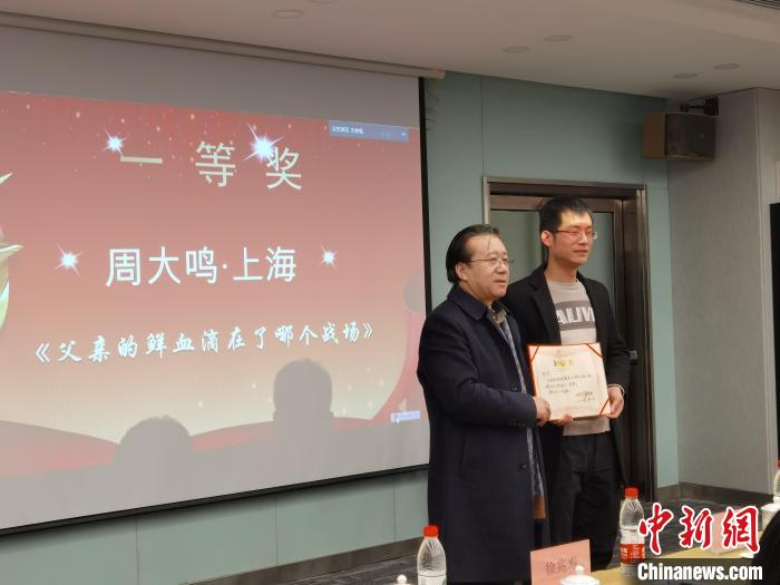 圖為作家、西北師范大學(xué)新聞與傳媒學(xué)院院長徐兆壽頒發(fā)一等獎證書，代領(lǐng)獎?wù)呱吓_領(lǐng)獎?！钅?攝