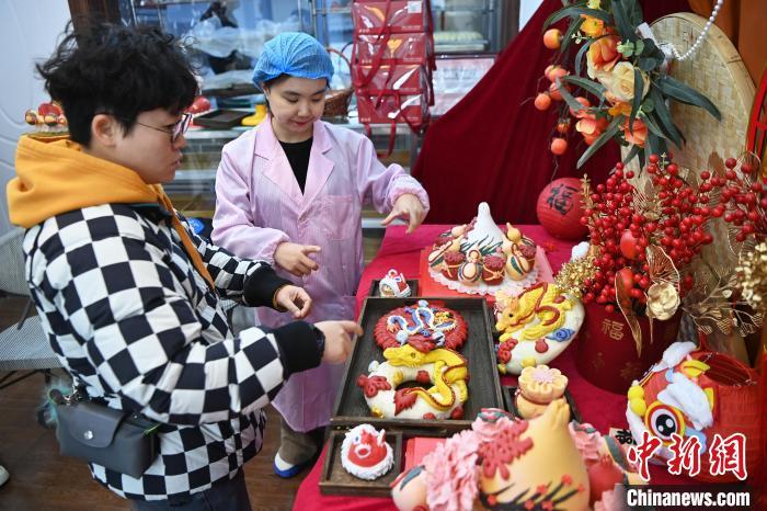 1月25日，隨著春節(jié)臨近，蘭州一花饃店“龍”元素花饃熱銷。圖為工作人員向顧客推薦“龍”元素花饃。九美旦增 攝</p><p>