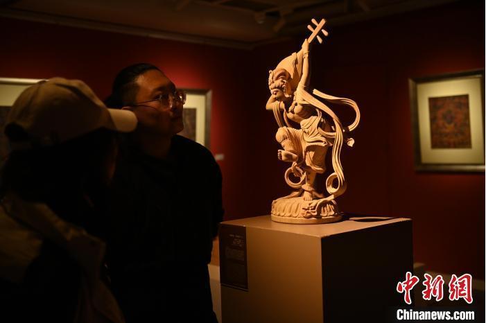 圖為季茂杰向參觀者介紹自己創(chuàng)作敦煌木雕的過程。李亞龍 攝</p>
<p>
