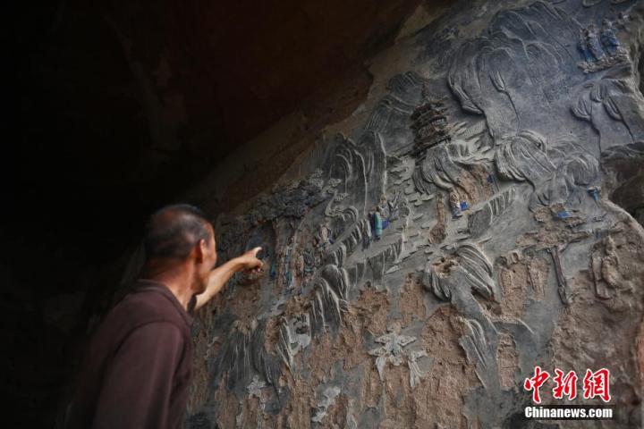 7月15日，甘肅省平?jīng)鍪袥艽h百里石窟長(zhǎng)廊羅漢洞石窟內(nèi)，該窟文保員郭建平介紹窟內(nèi)石刻彩繪壁畫(huà)。郭建平家中三代人曾自發(fā)保護(hù)羅漢洞石窟。羅漢洞石窟遺存40余個(gè)窟龕，以北魏至清代風(fēng)格為主。中新社記者 李亞龍 攝